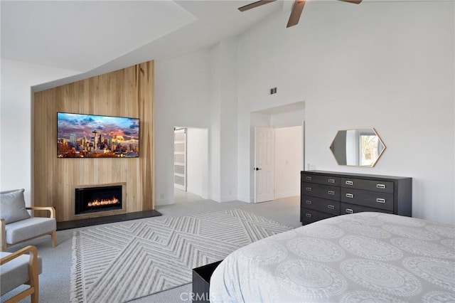 carpeted bedroom with ceiling fan and high vaulted ceiling