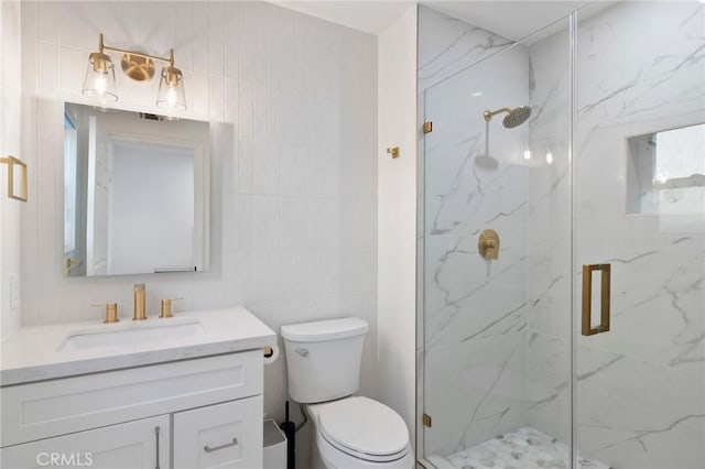 bathroom featuring vanity, toilet, a shower with door, and tile walls