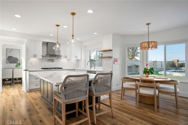 kitchen with pendant lighting, white cabinets, gas stovetop, and wall chimney exhaust hood