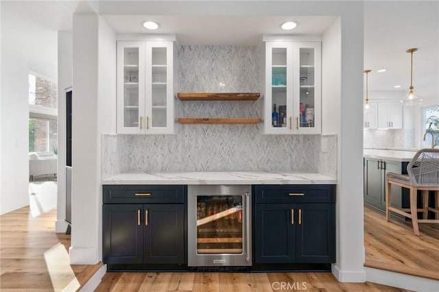 bar with wine cooler, white cabinetry, a wealth of natural light, and light hardwood / wood-style floors