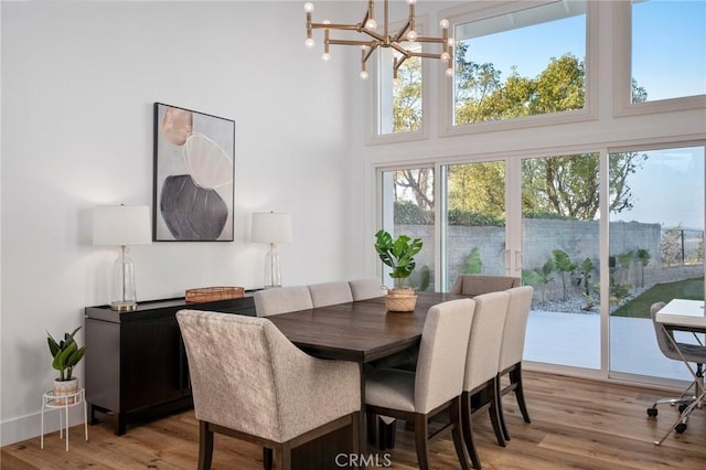 dining area featuring a high ceiling, an inviting chandelier, and light hardwood / wood-style flooring