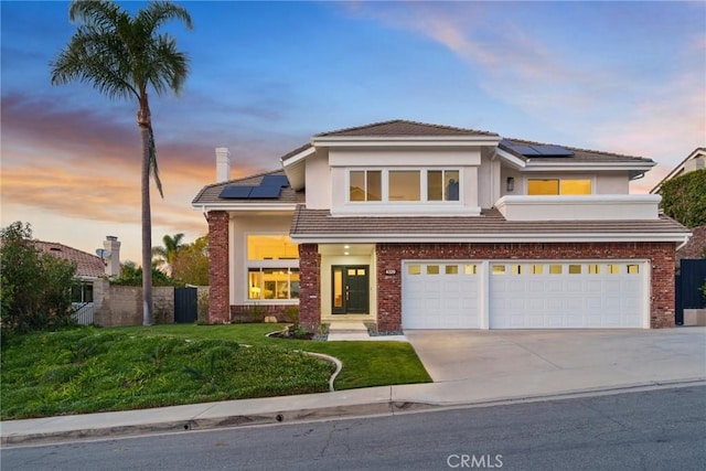 view of front of house featuring a garage, a yard, and solar panels