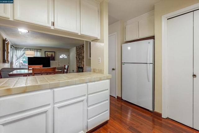 kitchen with dark wood-type flooring, tile countertops, white cabinets, and white refrigerator