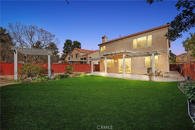 back house at dusk with a patio, a pergola, and a lawn