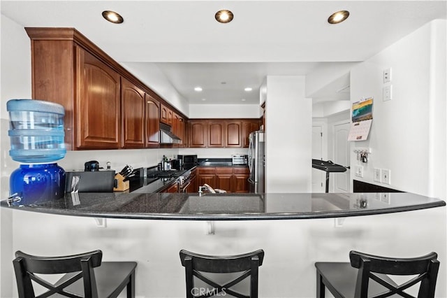 kitchen featuring appliances with stainless steel finishes, a kitchen bar, and kitchen peninsula