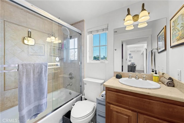 full bathroom featuring vanity, combined bath / shower with glass door, and toilet