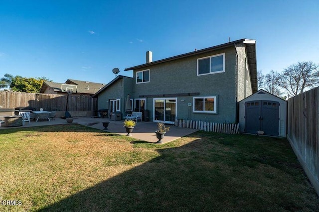 rear view of property featuring a patio, a fire pit, a yard, and a storage shed