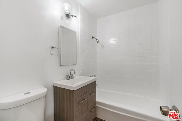 full bathroom featuring vanity, tiled shower / bath, and toilet