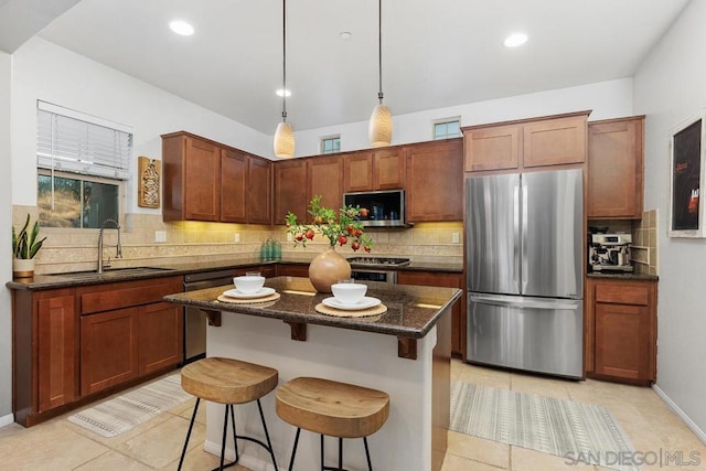 kitchen with pendant lighting, sink, a breakfast bar area, stainless steel appliances, and a kitchen island