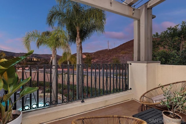 balcony at dusk featuring a mountain view