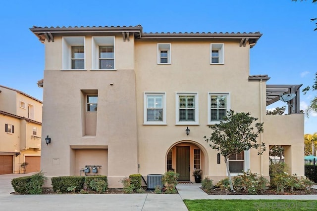 view of front of home featuring a garage, central AC unit, and a pergola