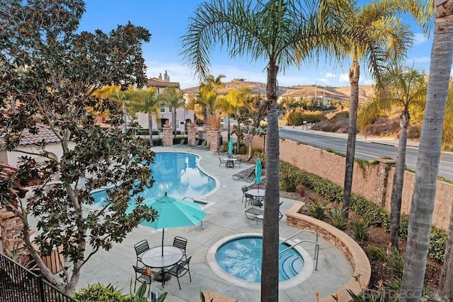 view of pool featuring a hot tub, a mountain view, and a patio