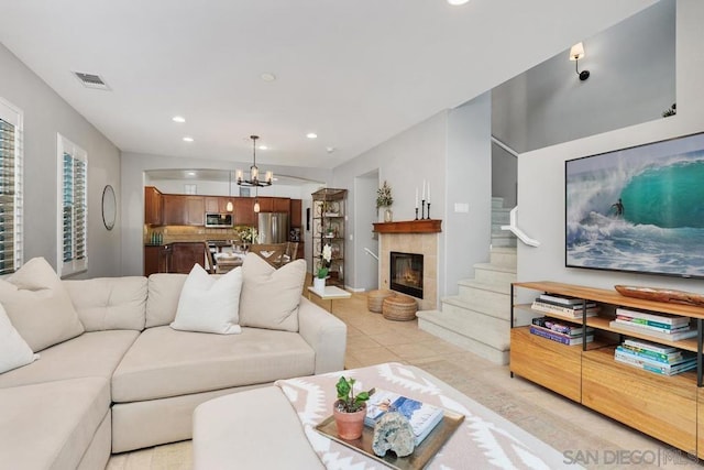 living room with light tile patterned floors, a fireplace, and a chandelier