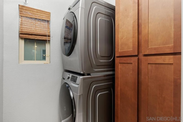 laundry room with cabinets and stacked washer and clothes dryer