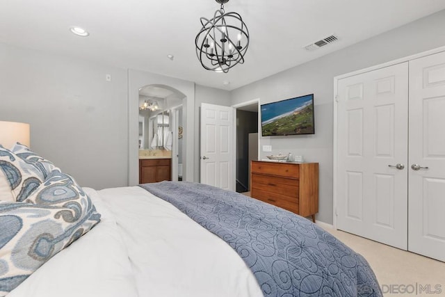 bedroom featuring a closet, connected bathroom, a chandelier, and light carpet