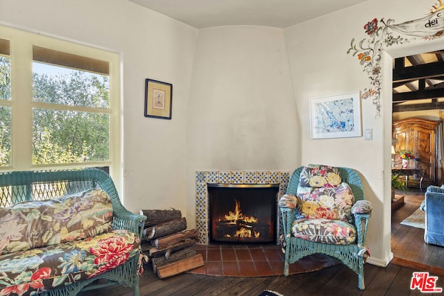 living area with a tiled fireplace and dark hardwood / wood-style flooring