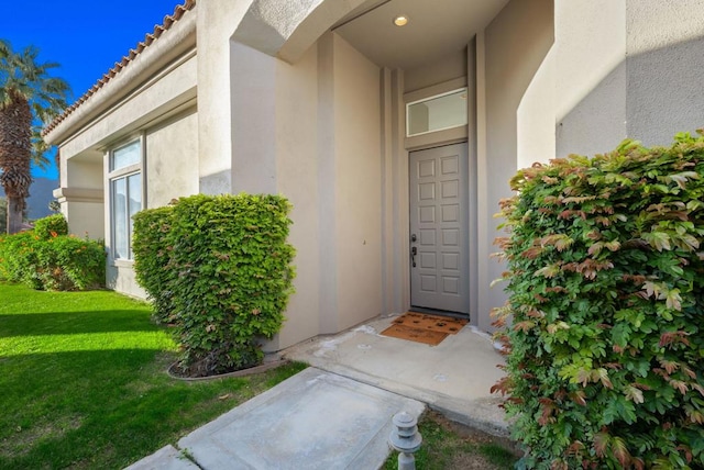 view of exterior entry featuring a lawn