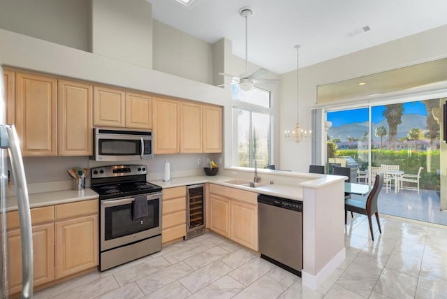 kitchen featuring sink, appliances with stainless steel finishes, wine cooler, light brown cabinetry, and kitchen peninsula