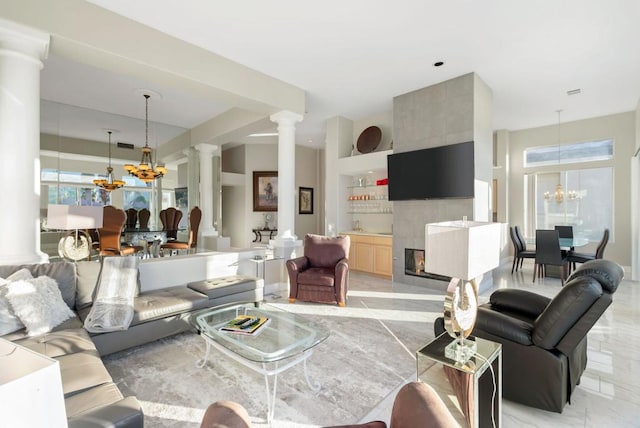 living room with ornate columns, plenty of natural light, a chandelier, and built in shelves