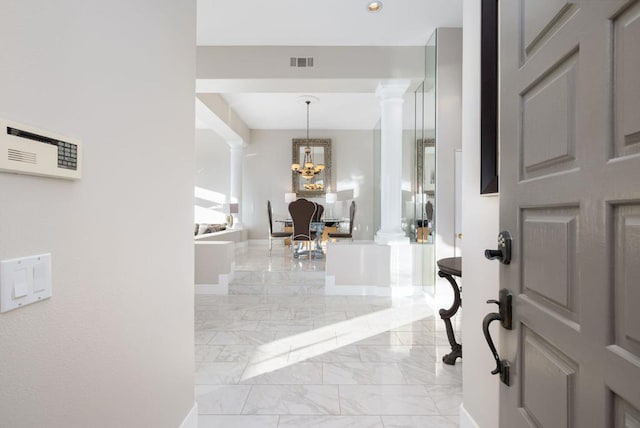 entrance foyer featuring decorative columns and a notable chandelier