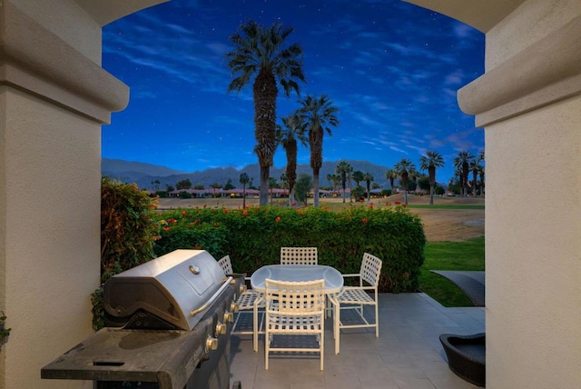 patio terrace at dusk featuring a grill