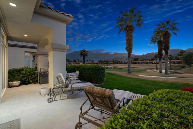 patio terrace at dusk with exterior kitchen, area for grilling, and a mountain view