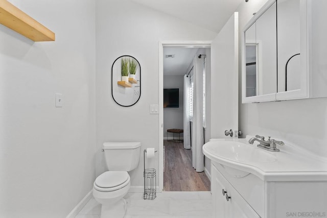 bathroom featuring vanity, lofted ceiling, and toilet