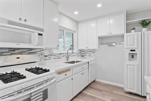 kitchen with sink, white cabinetry, tasteful backsplash, light hardwood / wood-style flooring, and white appliances