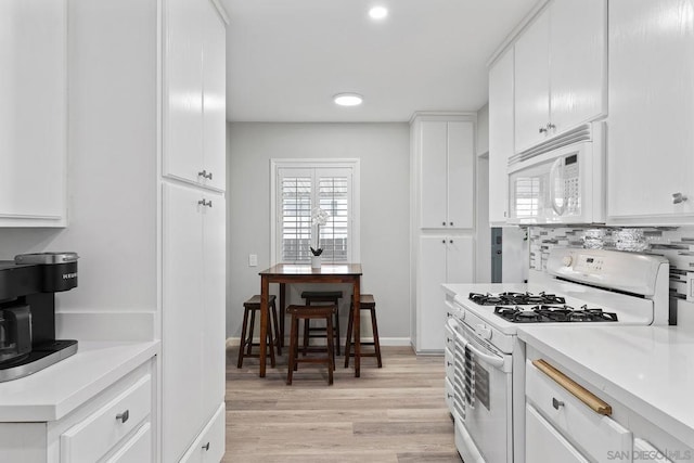 kitchen with white cabinetry, white appliances, plenty of natural light, and backsplash