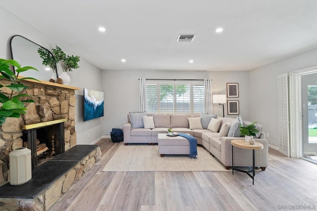 living room featuring a healthy amount of sunlight, a fireplace, and light hardwood / wood-style flooring