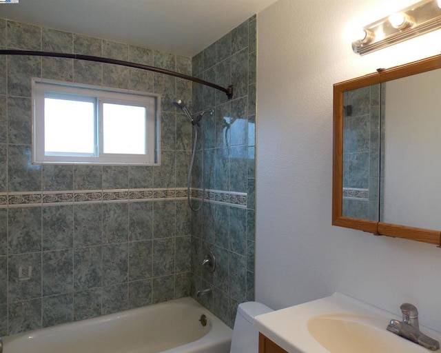 full bathroom with tiled shower / bath, vanity, and toilet