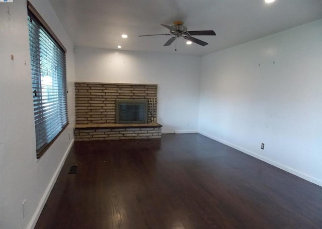 unfurnished living room featuring dark wood-type flooring, ceiling fan, and a fireplace