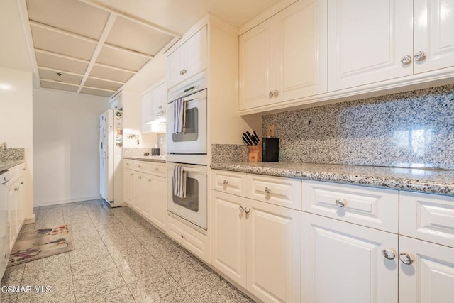 kitchen with light stone countertops, white cabinets, white appliances, and decorative backsplash