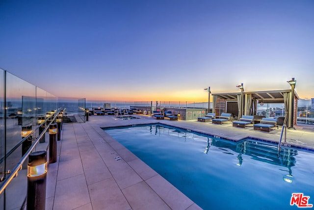 pool at dusk featuring a patio