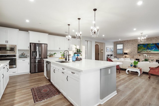 kitchen featuring white cabinetry, appliances with stainless steel finishes, sink, and a center island with sink