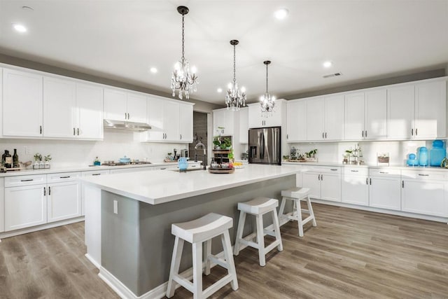 kitchen featuring white cabinetry, stainless steel appliances, a kitchen island with sink, and pendant lighting