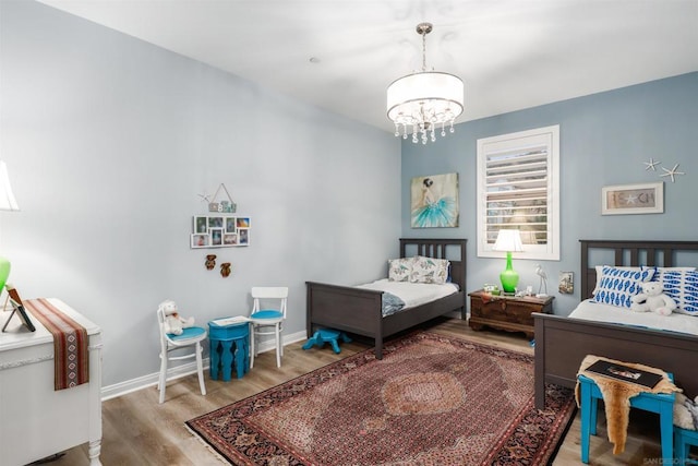 bedroom featuring an inviting chandelier and light hardwood / wood-style flooring