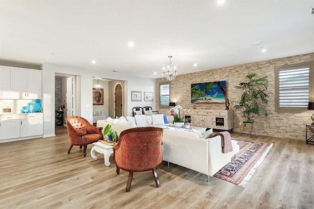 living room with a fireplace, an inviting chandelier, and light hardwood / wood-style flooring