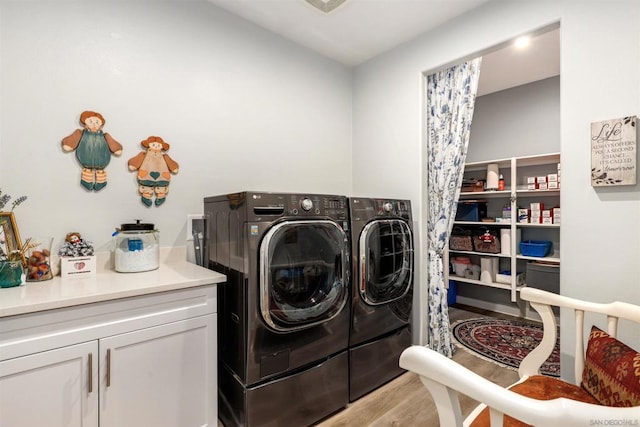 laundry room with cabinets, independent washer and dryer, and light wood-type flooring