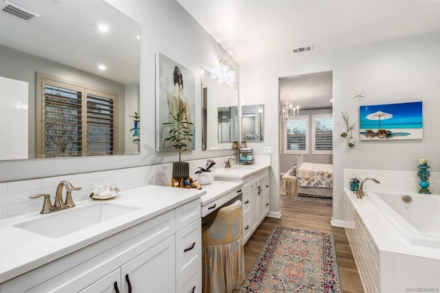 bathroom with vanity, hardwood / wood-style floors, decorative backsplash, and tiled bath