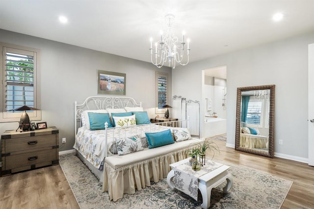 bedroom with an inviting chandelier, light wood-type flooring, and ensuite bath