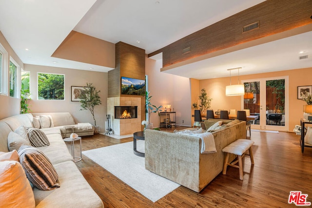 living room with a tiled fireplace and wood-type flooring