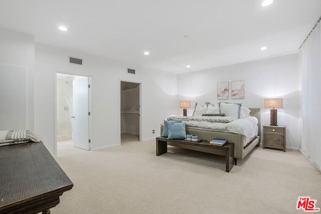 bedroom featuring connected bathroom, a spacious closet, and light colored carpet