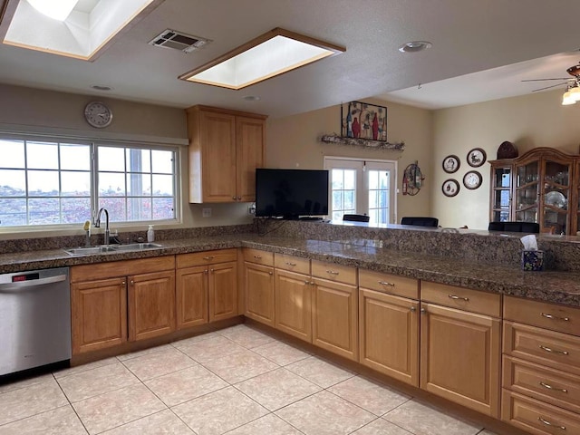 kitchen featuring sink, a skylight, light tile patterned floors, dishwasher, and ceiling fan