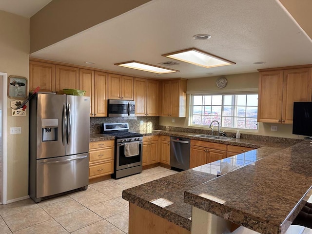 kitchen with appliances with stainless steel finishes, sink, light tile patterned floors, and kitchen peninsula