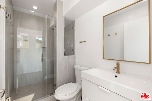 bathroom with vanity, a shower with shower door, and toilet