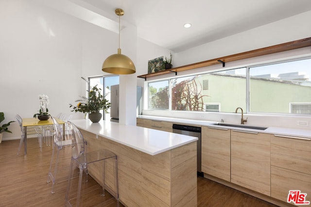 kitchen featuring a breakfast bar, sink, decorative light fixtures, stainless steel dishwasher, and dark hardwood / wood-style floors