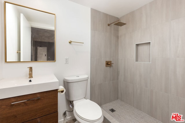 bathroom with vanity, toilet, and tiled shower