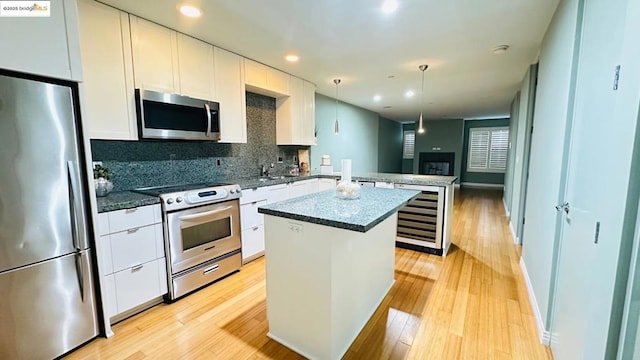 kitchen with pendant lighting, stainless steel appliances, a center island, and white cabinets