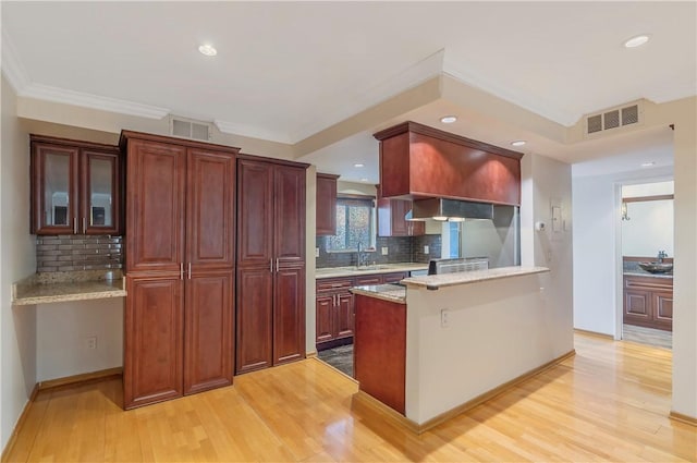 kitchen with sink, ornamental molding, light hardwood / wood-style floors, light stone countertops, and decorative backsplash